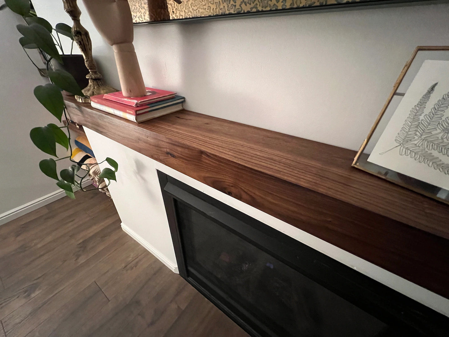 Close view of the installed wood beam floating fireplace mantel. The fireplace mantel has a smooth grain and a modern look.