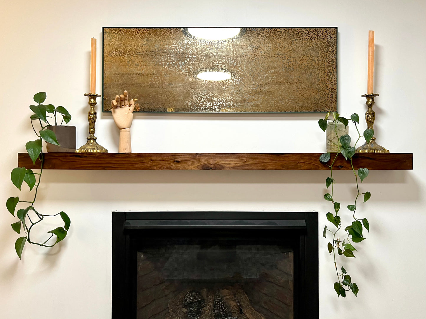 Front view of the installed floating wood beam or wood box fireplace mantel with decor. The fireplace mantel has a smooth finish and a modern look.