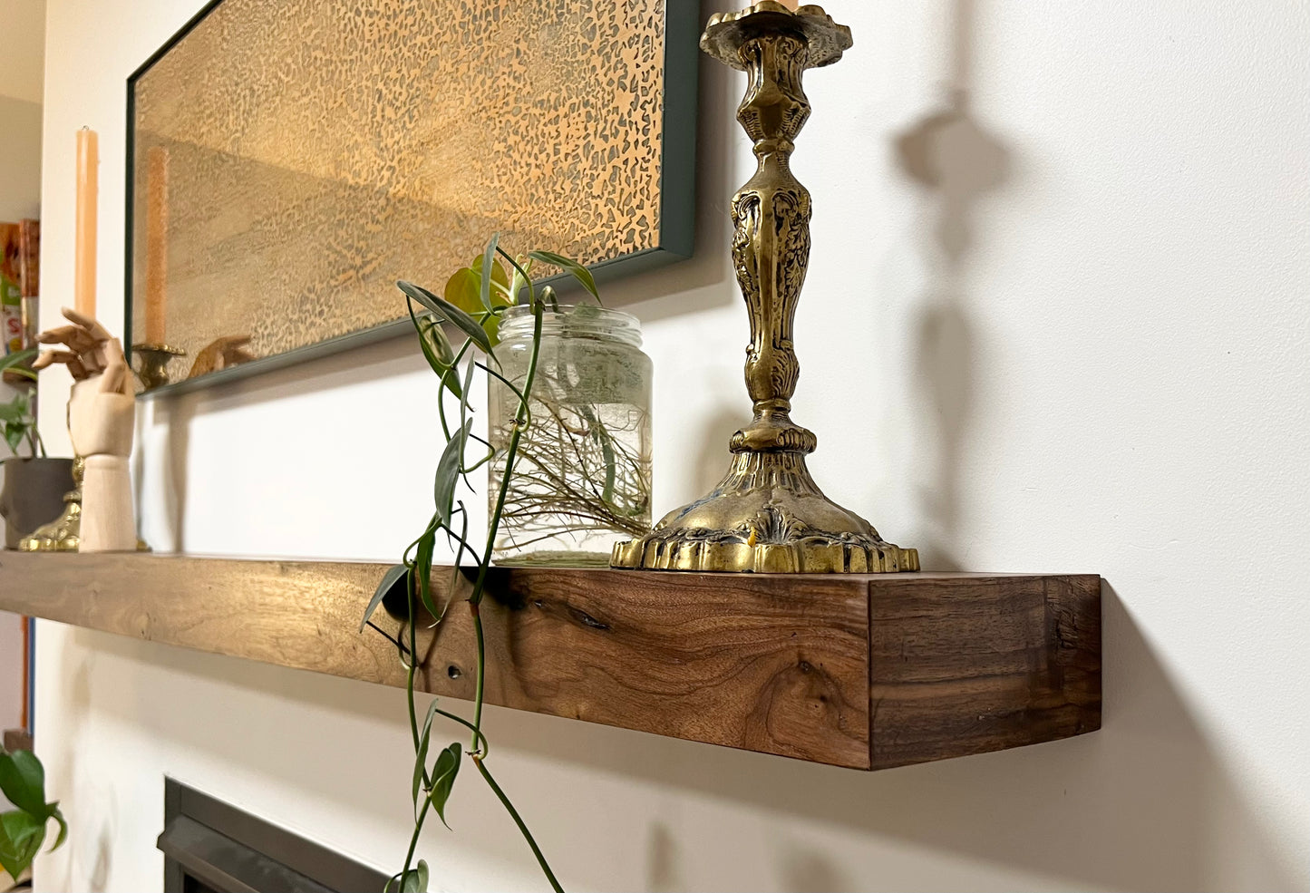Side view of the installed floating wood beam or wood box fireplace mantel with decor. The fireplace mantel has a smooth finish and a modern look.