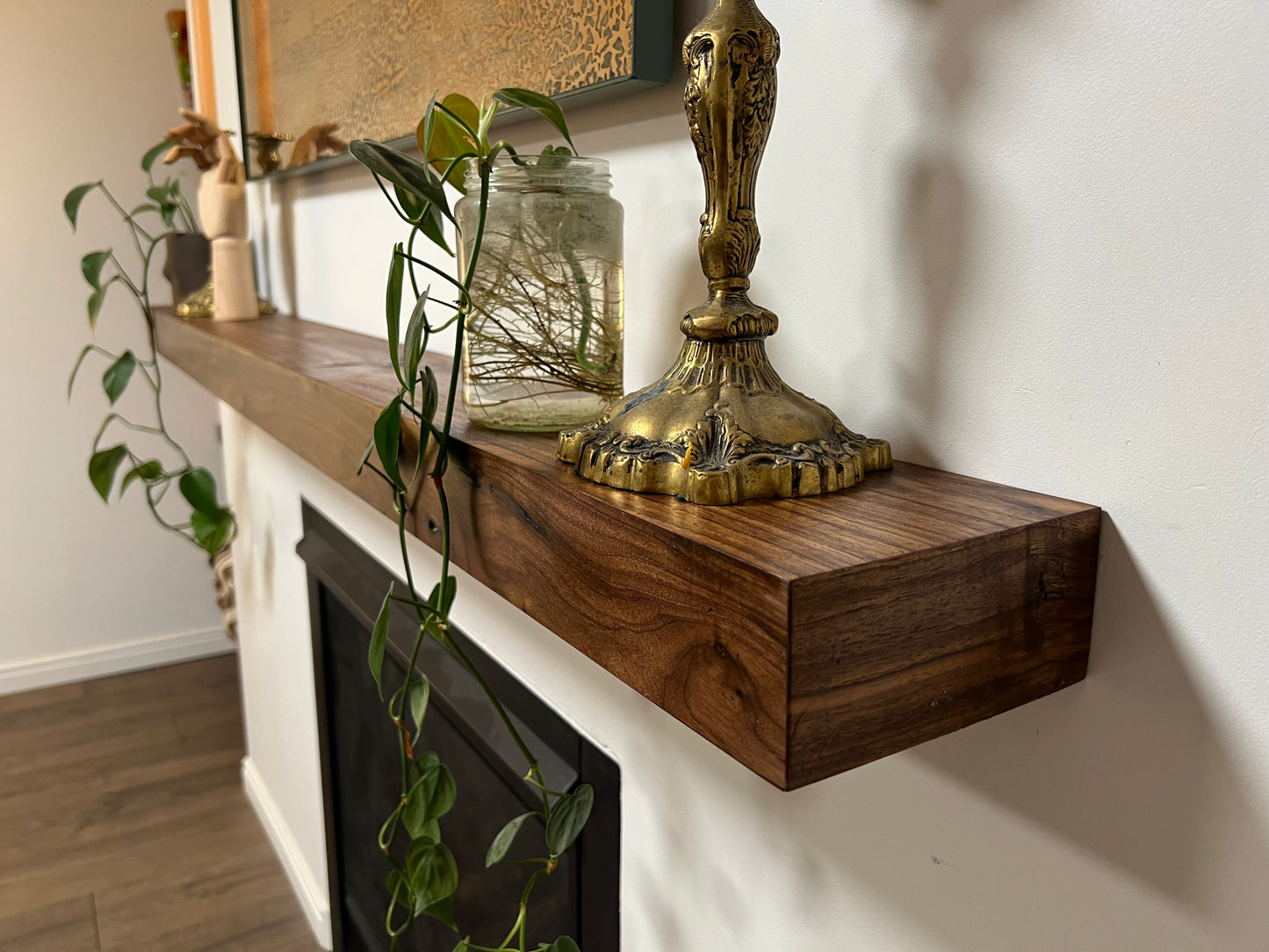 Side view of the installed floating wood beam or wood box fireplace mantel with decor. The fireplace mantel has a smooth finish and a modern look.