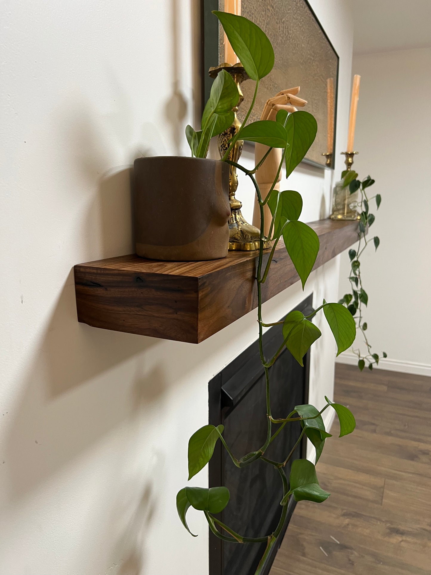 Side view of the installed floating wood beam or wood box fireplace mantel with decor. The fireplace mantel has a smooth finish and a modern look.