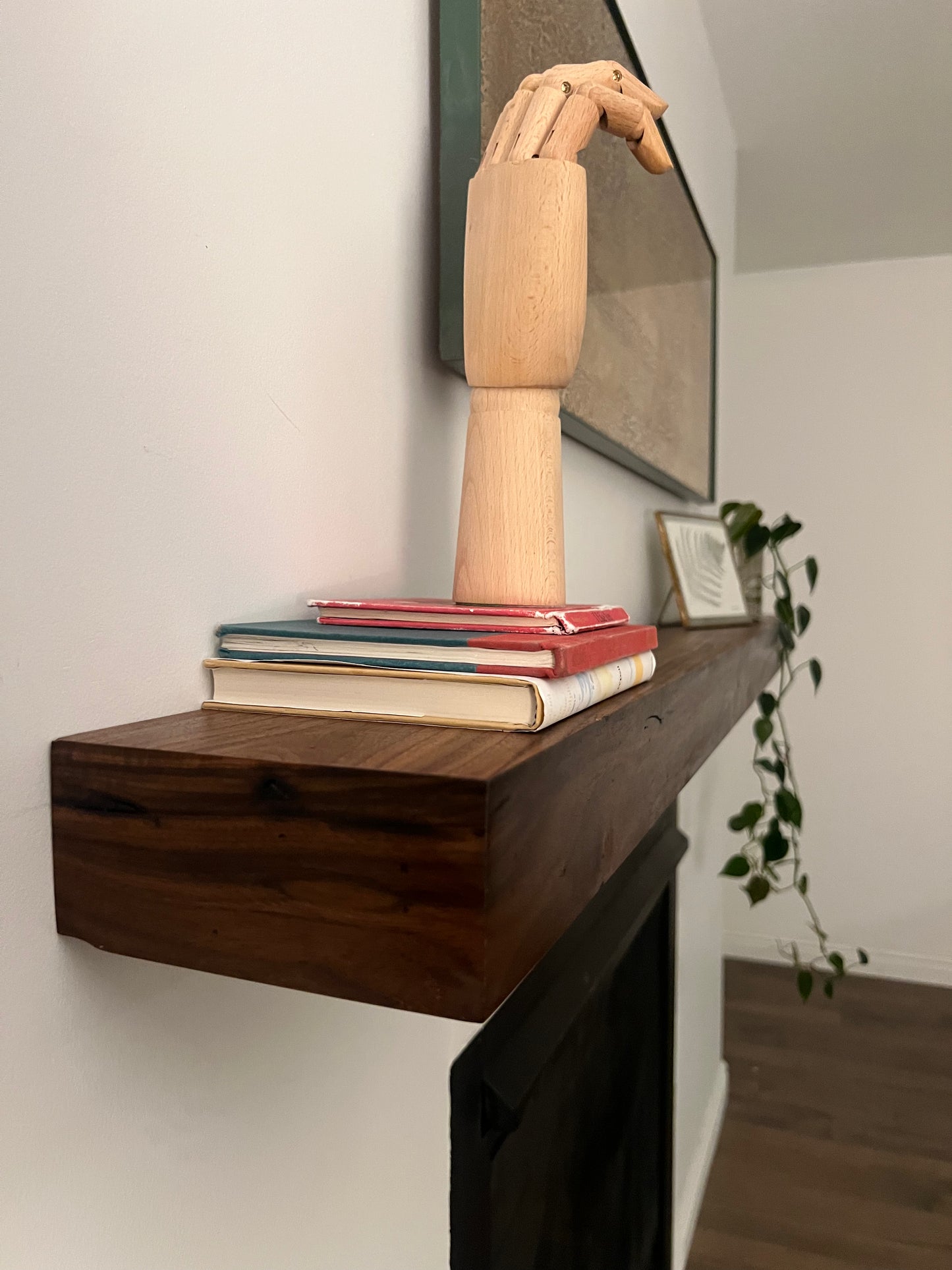 Side view of the installed floating wood beam or wood box fireplace mantel with decor. The fireplace mantel has a smooth finish and a modern look.