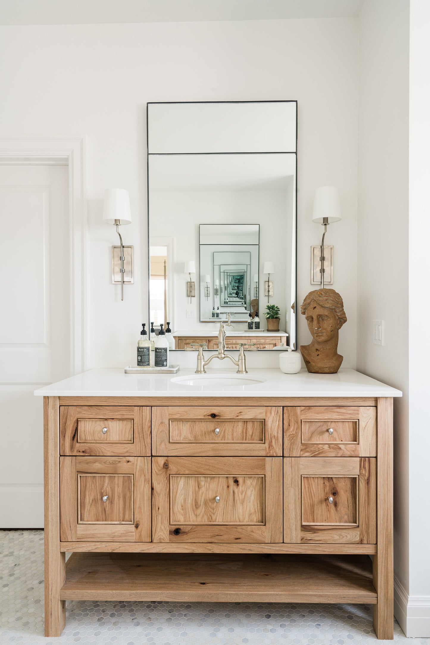 Custom steel framed inlaid mirror facing another mirror creating an infinity mirror. The mirror is wall mounted over a wood and marble vanity with classic styling.