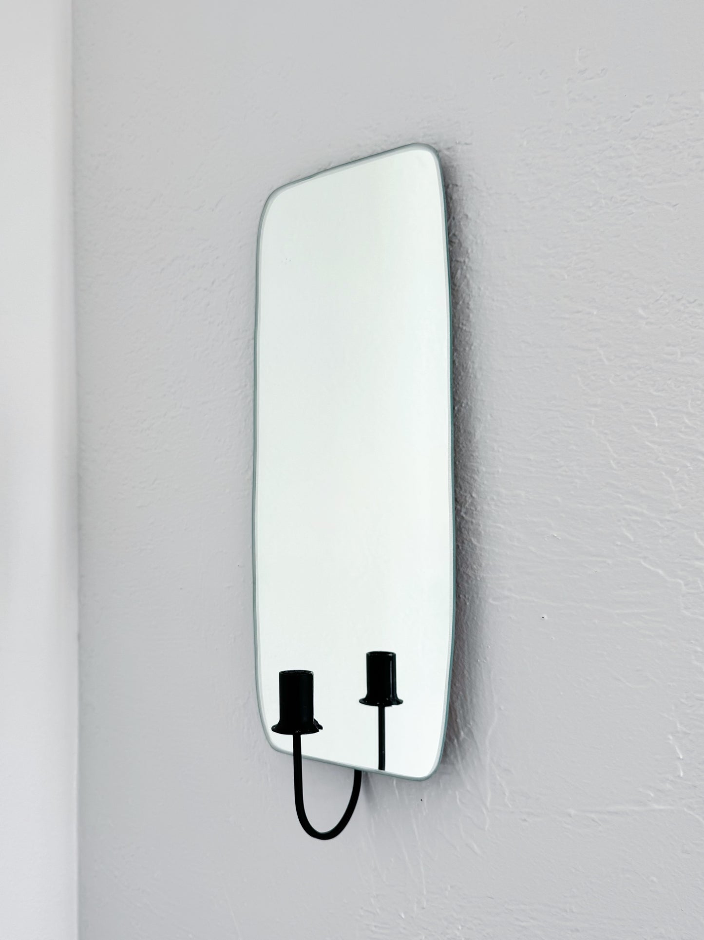 Side view of the Oar Mirror Candle Sconce or Mirror Candle Holder, wall mounted, reflecting the black candleholder and a white backdrop.